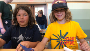 Two Camp Fire campers, one smiling brightly and wearing a bright yellow Spark t-shirt