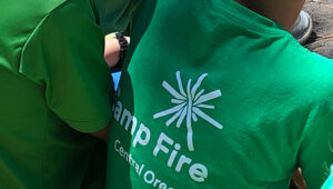 A close-up of the Camp Fire logo on a green shirt.