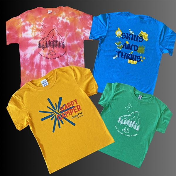 An assortment of Camp Fire t-shirts in bright colors. One says, Happy Camper.