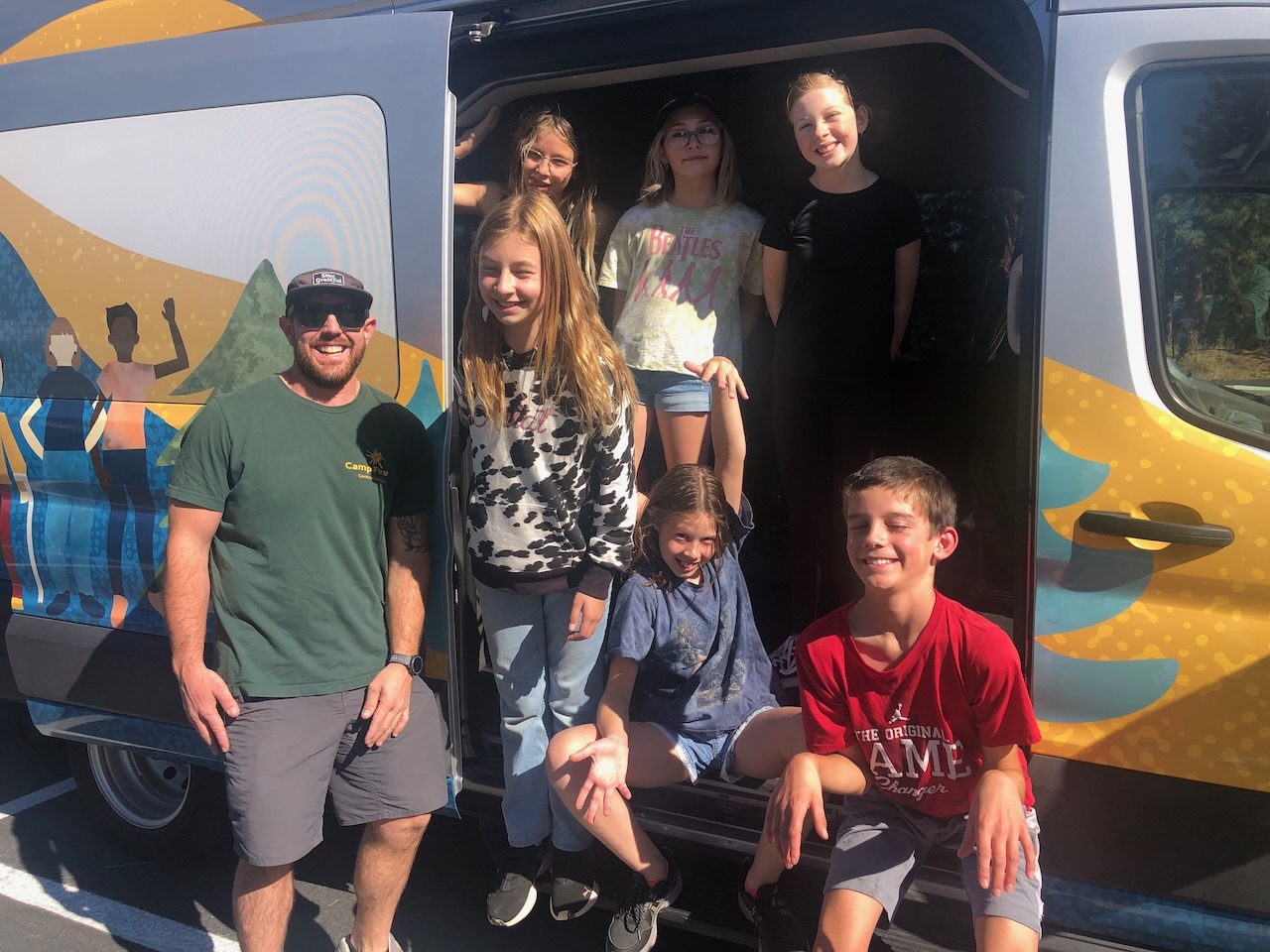 Camp Fire counselor James and 6 campers pose with Sparky the Van
