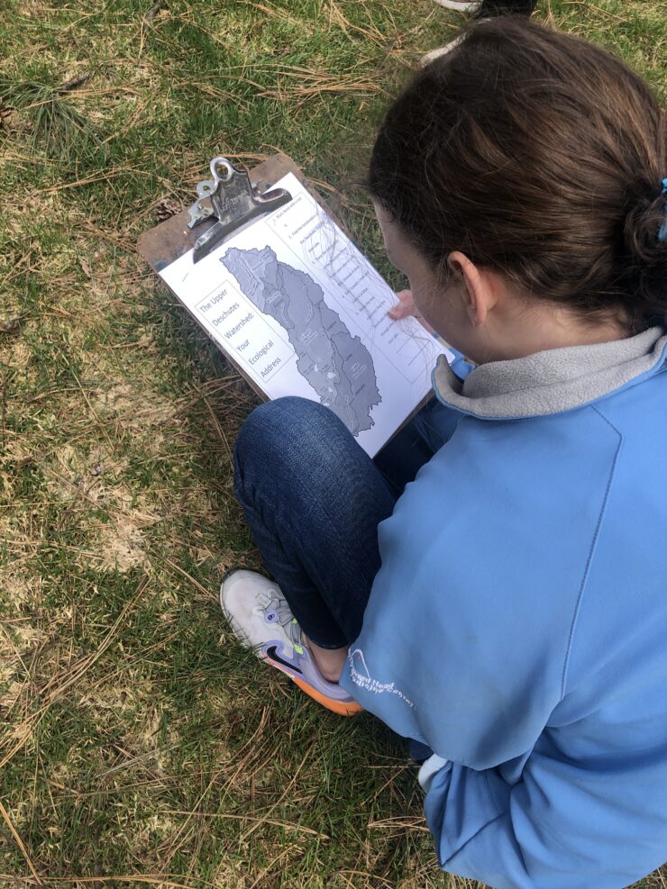 A teen volunteer studies a map of a Central Oregon watershed region.