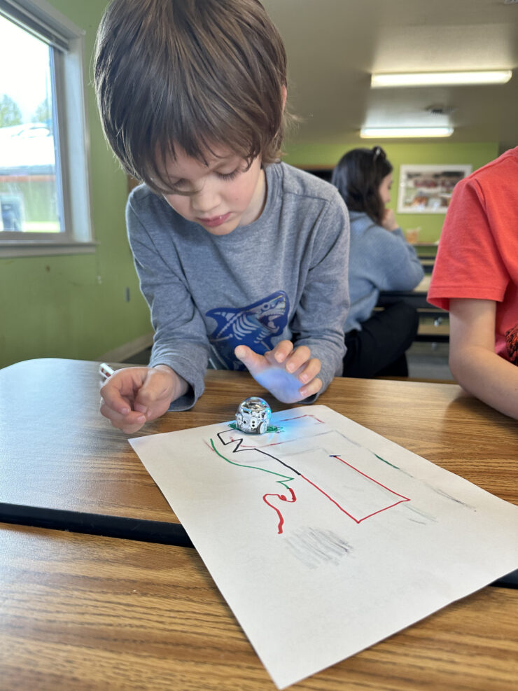 A boy looks in wonder at his Ozobot as it performs a command