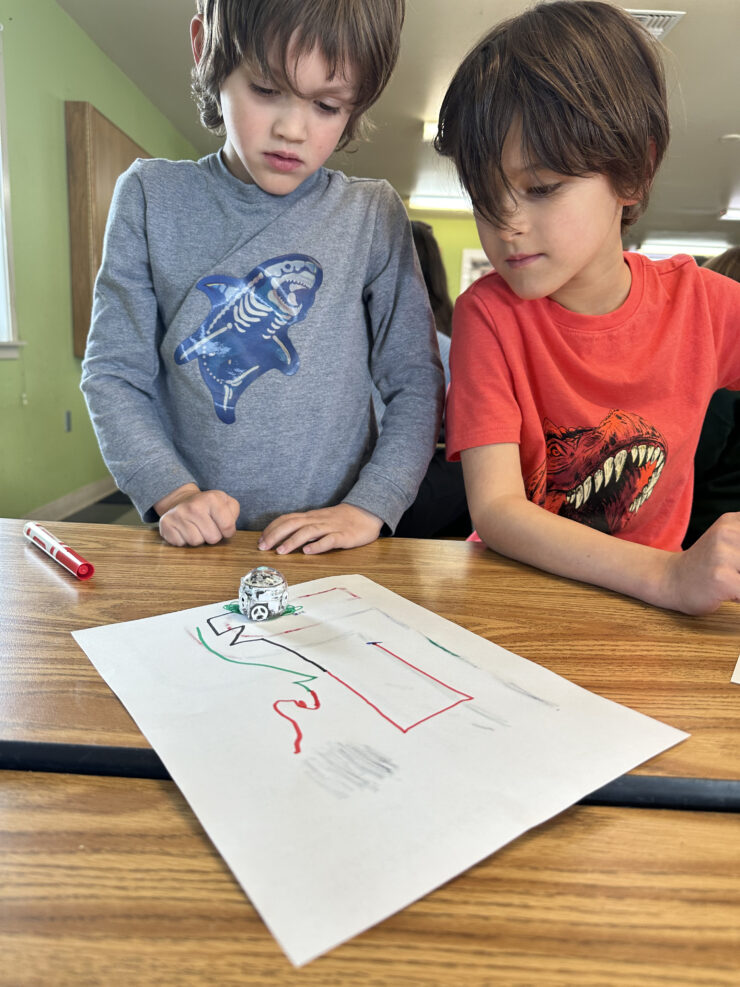 Two afterschool kids make their Ozobot perform tricks and tasks.