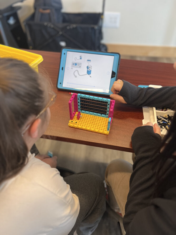 youth looking at iPad and using LEGOs® to assemble robotics parts