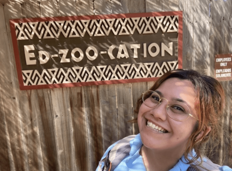 Cyrpianna stands next to a sign that promotes education at the zoo.