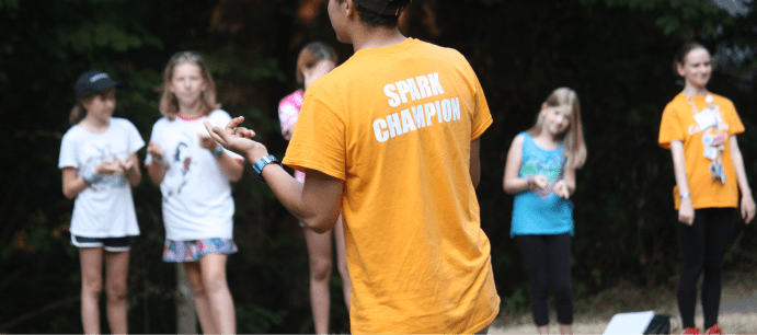 Camp counselor with t-shirt bearing the words "spark champion."