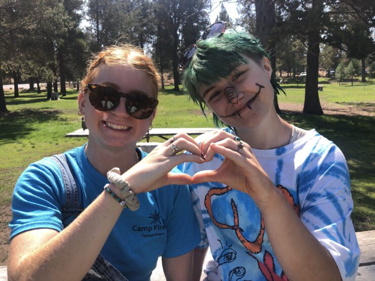 A camp counselor and Counselor in Training form a heart with their hands.