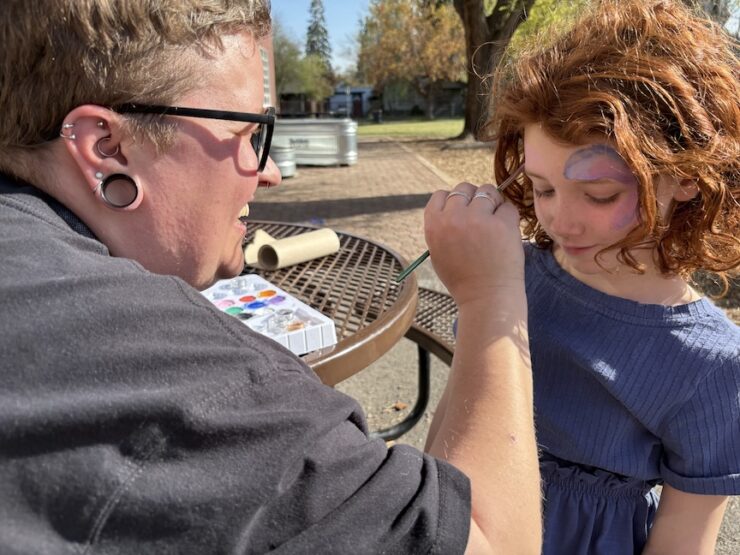 Camper getting facepaint put on her face by a staff member.