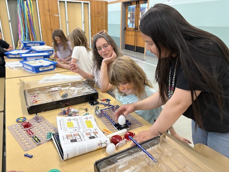 Staff member helps youth and parent with robotics.