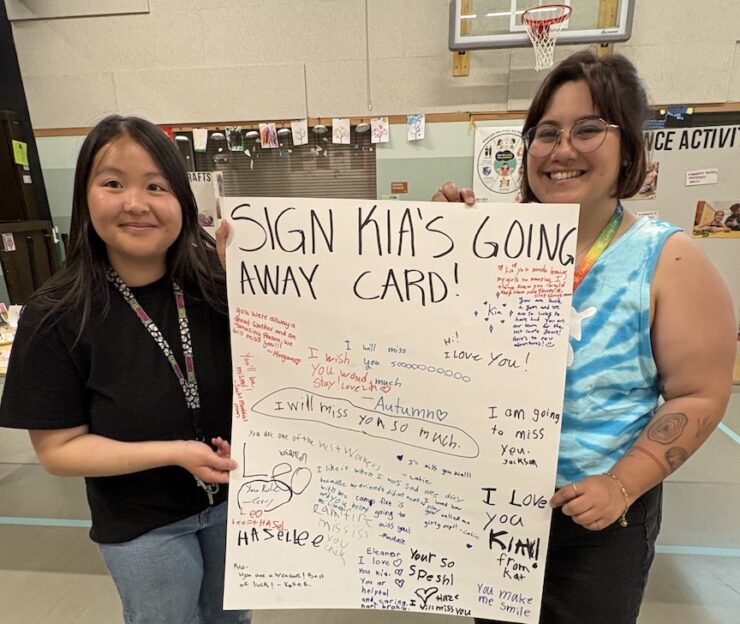 Staff members holding a signed posterboard for departing program coordinator.