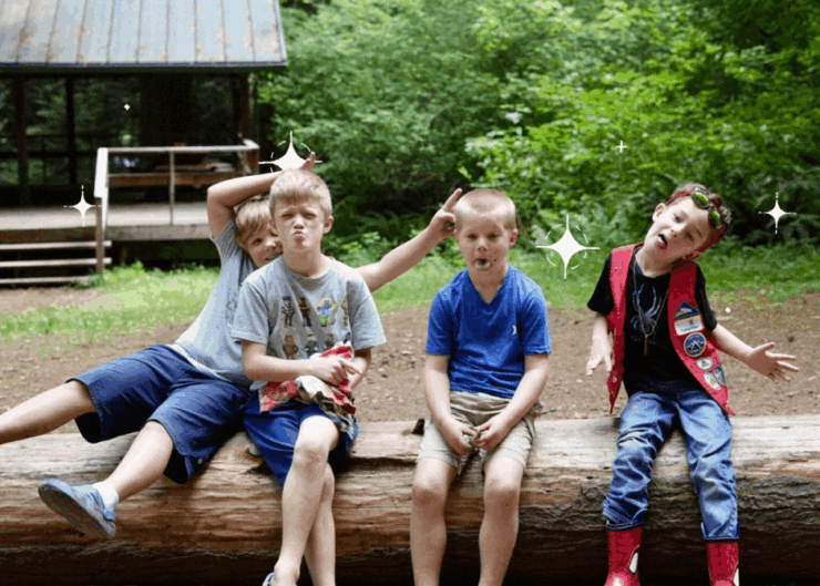 Campers sitting on a log acting silly.