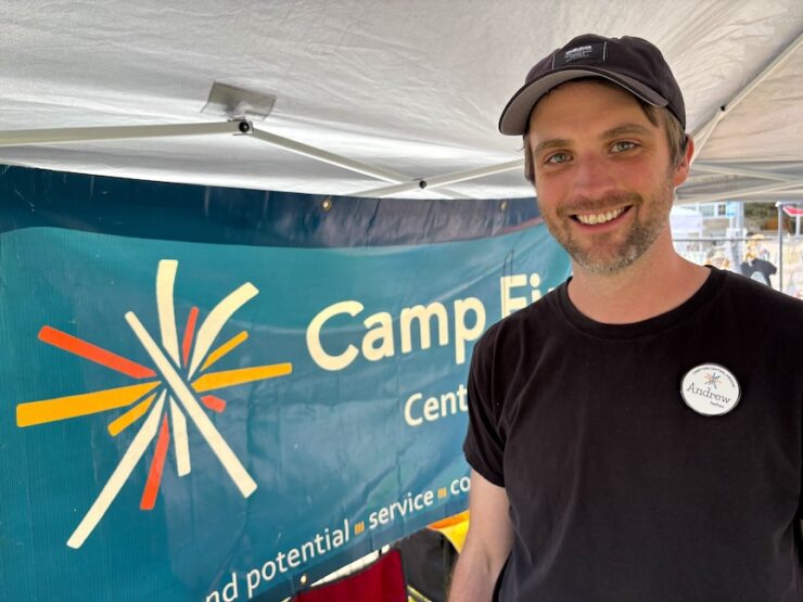 Andrew Blaylock poses in front of the Camp Fire banner.