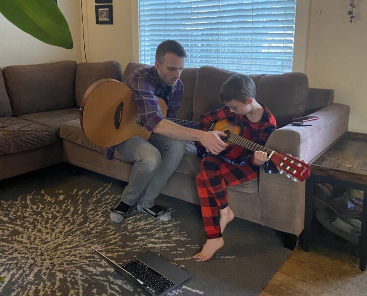 Andrew Blaylock shows a youth how to play the guitar.