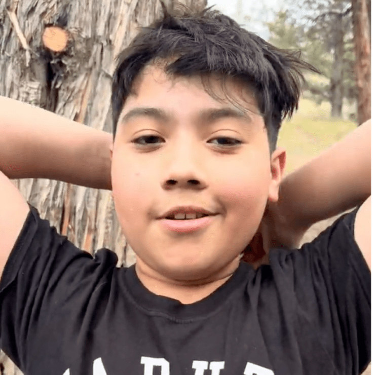 Boy with arms behind his head.