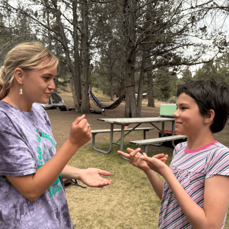 Camper and camp counselor play rock paper scissors at camp.