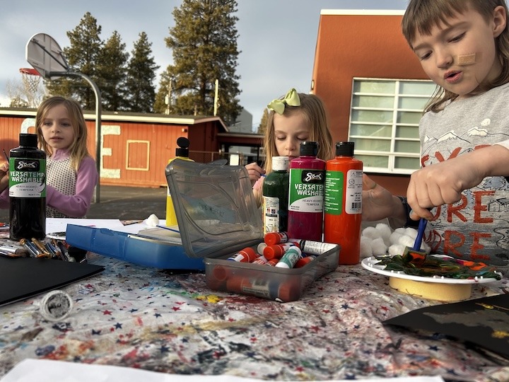 Youth playing with paint at a picnic table.