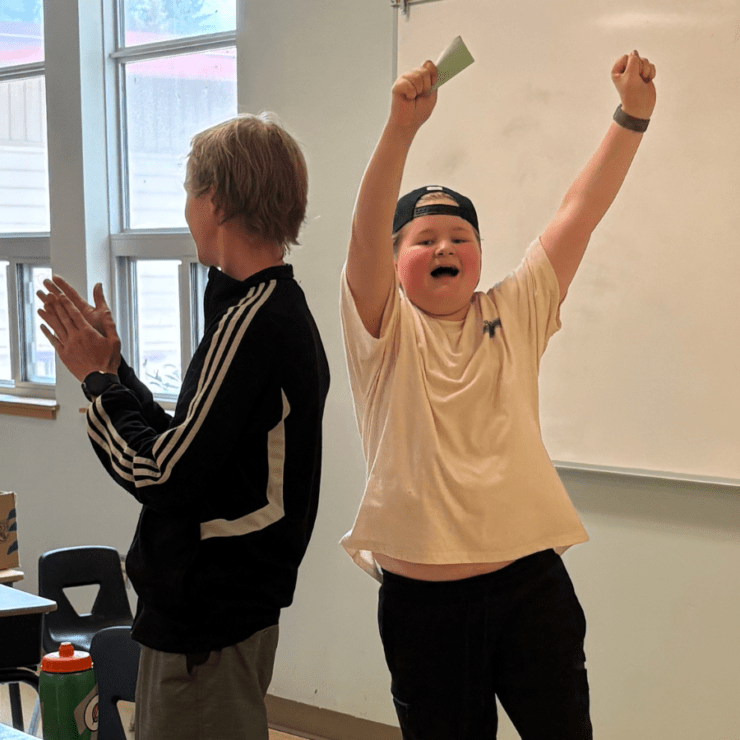Boy cheering at front of room.