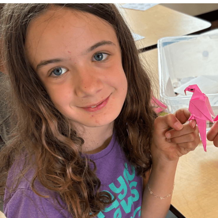 Camper holding origami parrot.