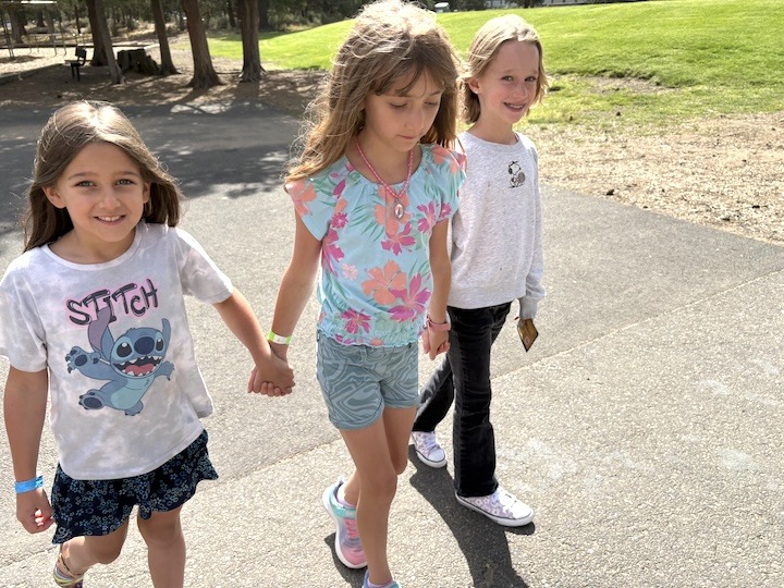 Three campers holding hands in friendship on the playground.