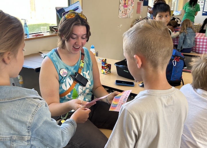 SummerKids youth hand a Camp Counselor a kindness card.