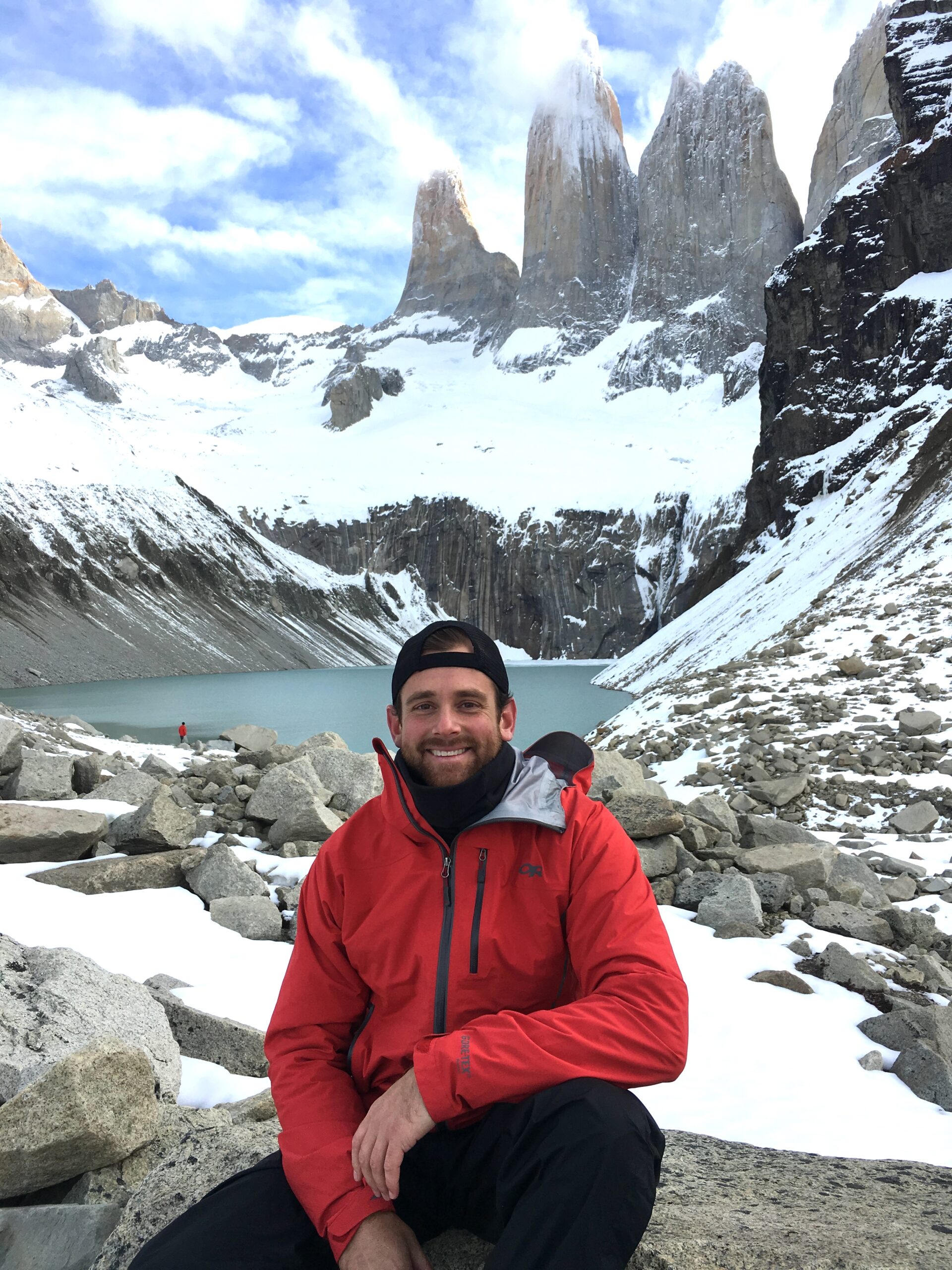 Morgan Schaening sitting in snow at the base of the mountains.