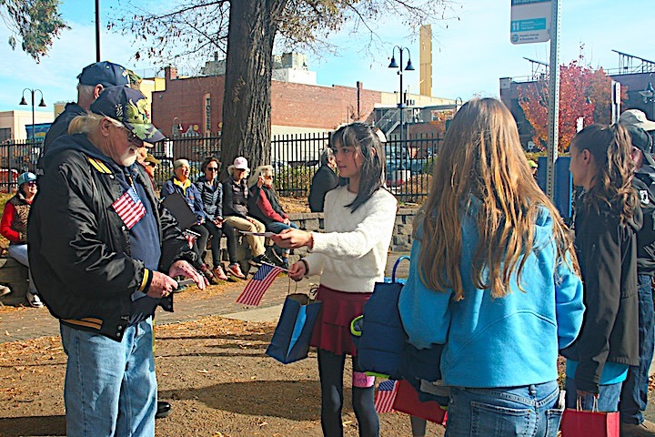 Teen handing U.S. veteran a thank-you card.