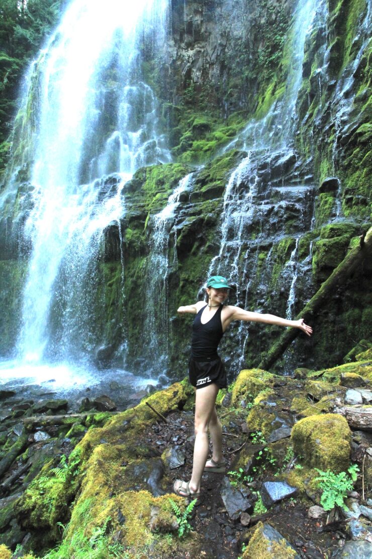 Kamryn Sherman stands in front of a waterfall.