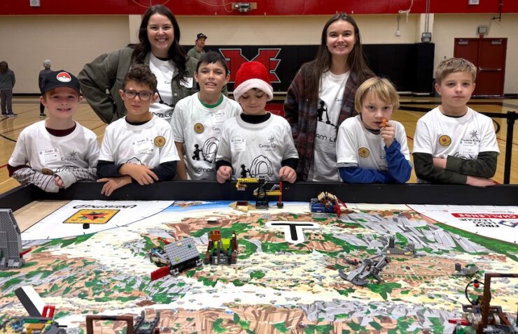 Youth and robotics staff around a LEGO robotics table.